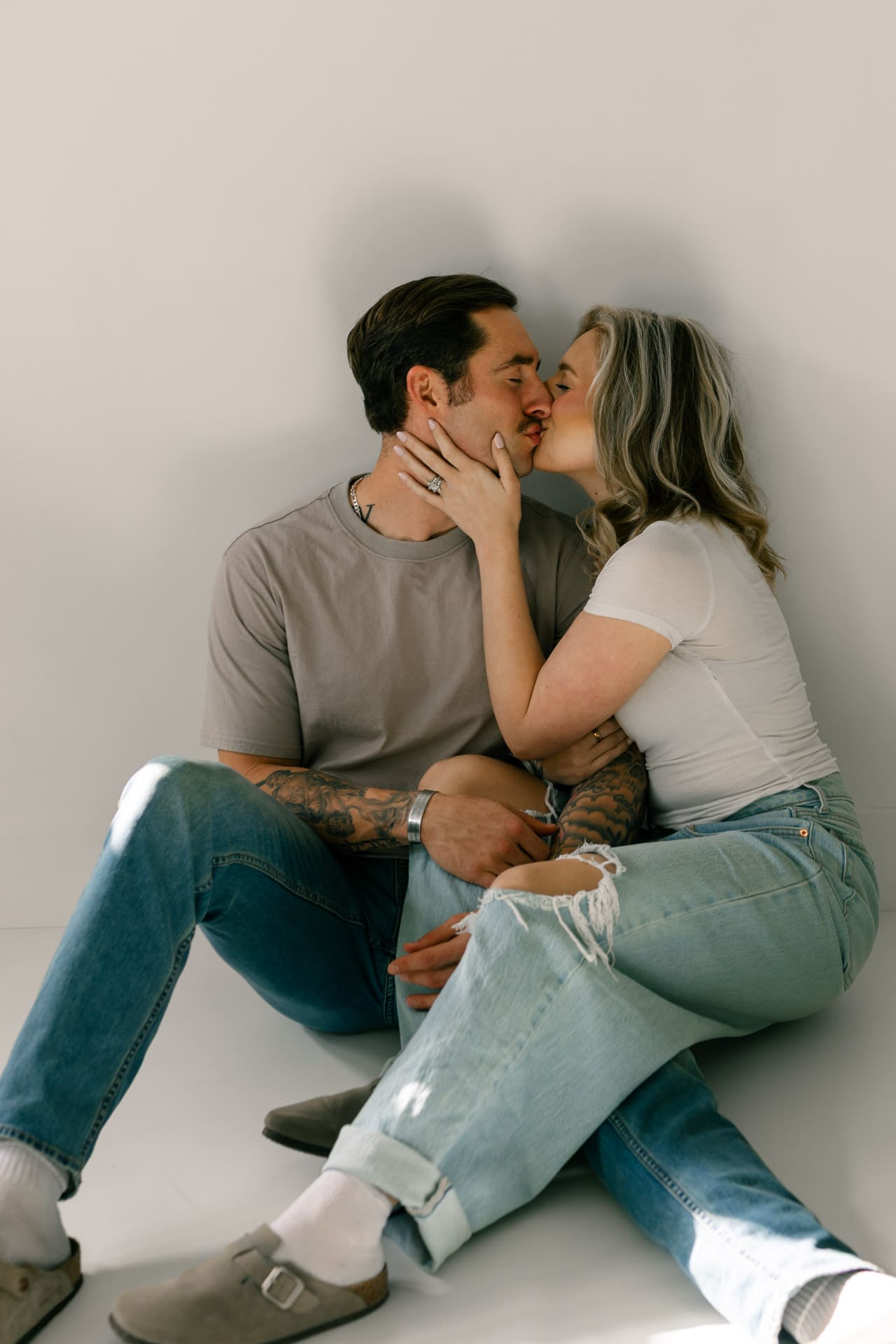 Couple photoshoot in studio in Goldsboro, NC. Couple cuddling playfully while sitting together.