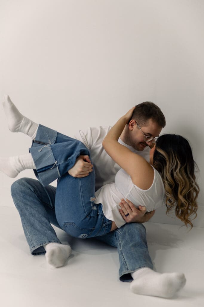 Couple in studio near Goldsboro, North Carolina. Sitting on floor in relaxed, fun, playful position.